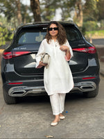 Woman in a white outfit standing next to a black Mercedes-Benz GLC 300 car.