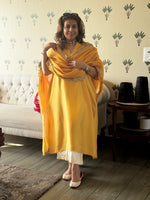 Woman in a yellow traditional outfit standing in a living room.