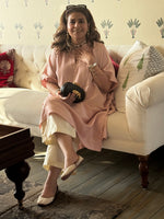Woman sitting on a couch holding a black clutch in a living room.