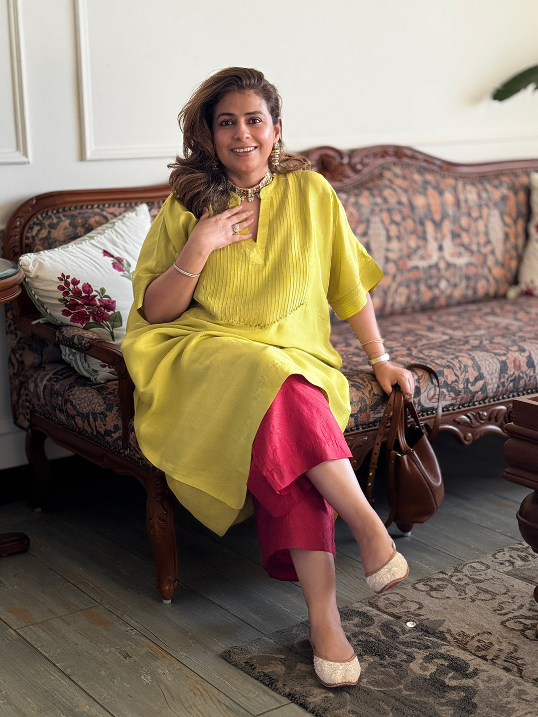 Woman in a yellow top and pink skirt sitting on a patterned sofa.