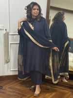 Woman wearing a dark black traditional silk kurta with gold trim on placket. Paired with Dupatta.