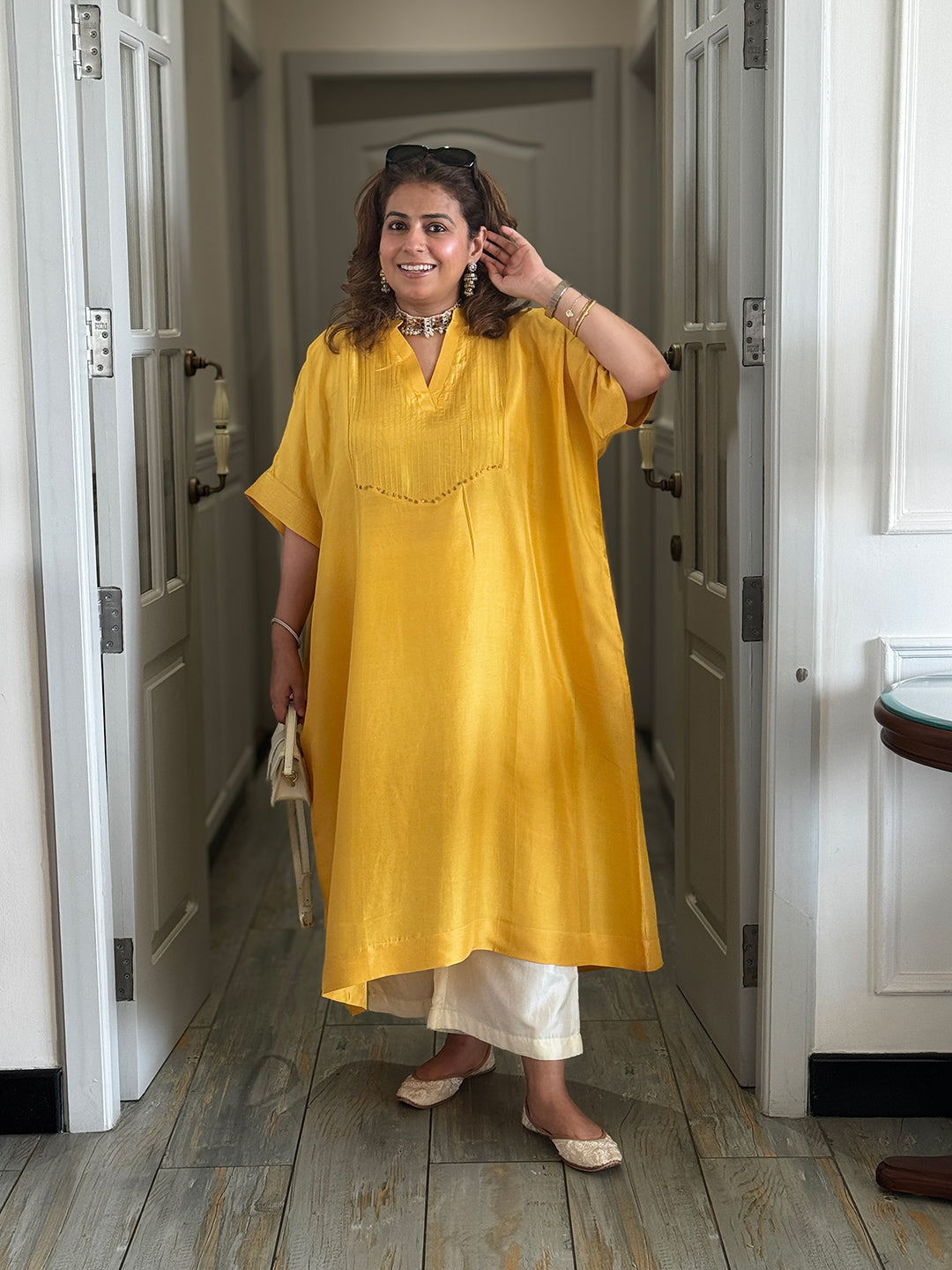 Woman wearing a yellow dress standing in a hallway.