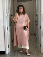 Woman in a pink dress standing in a hallway holding a Sabyasachi clutch.