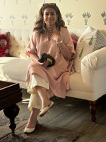 Woman sitting on a couch holding a black clutch in a living room.