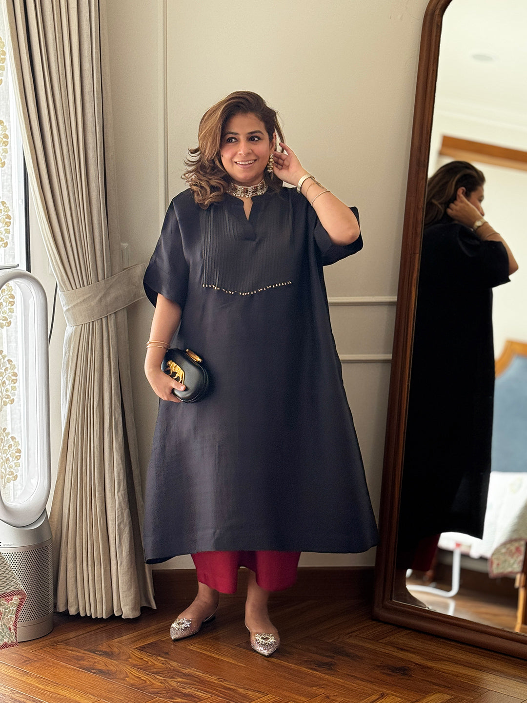 Woman in a charcoal black with red bottom standing in front of a mirror.