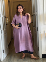 Woman wearing a purple dress standing in a doorway.
