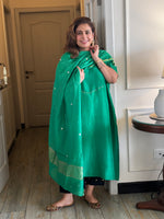 Woman wearing a green traditional outfit indoors.