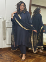 Woman wearing a dark black traditional silk kurta with gold trim on placket. Paired with Dupatta. 