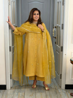 Woman in a yellow traditional outfit standing in a doorway.